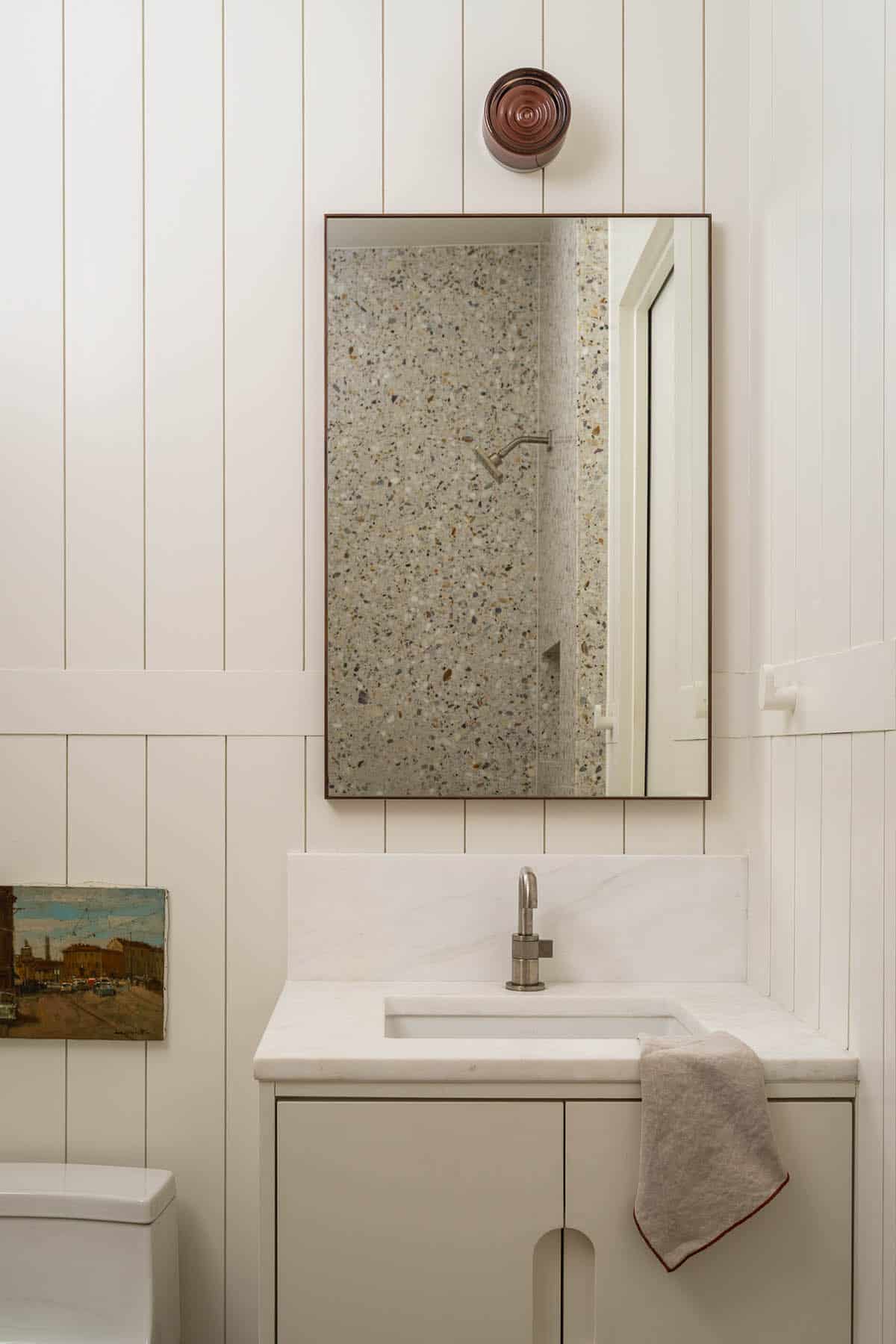 Powder room with shiplap walls and a terrazzo shower reflected in the mirror