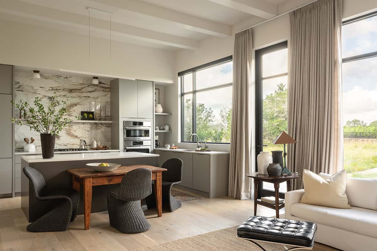 Kitchen island with woven chairs and reclaimed wood table facing garden doors