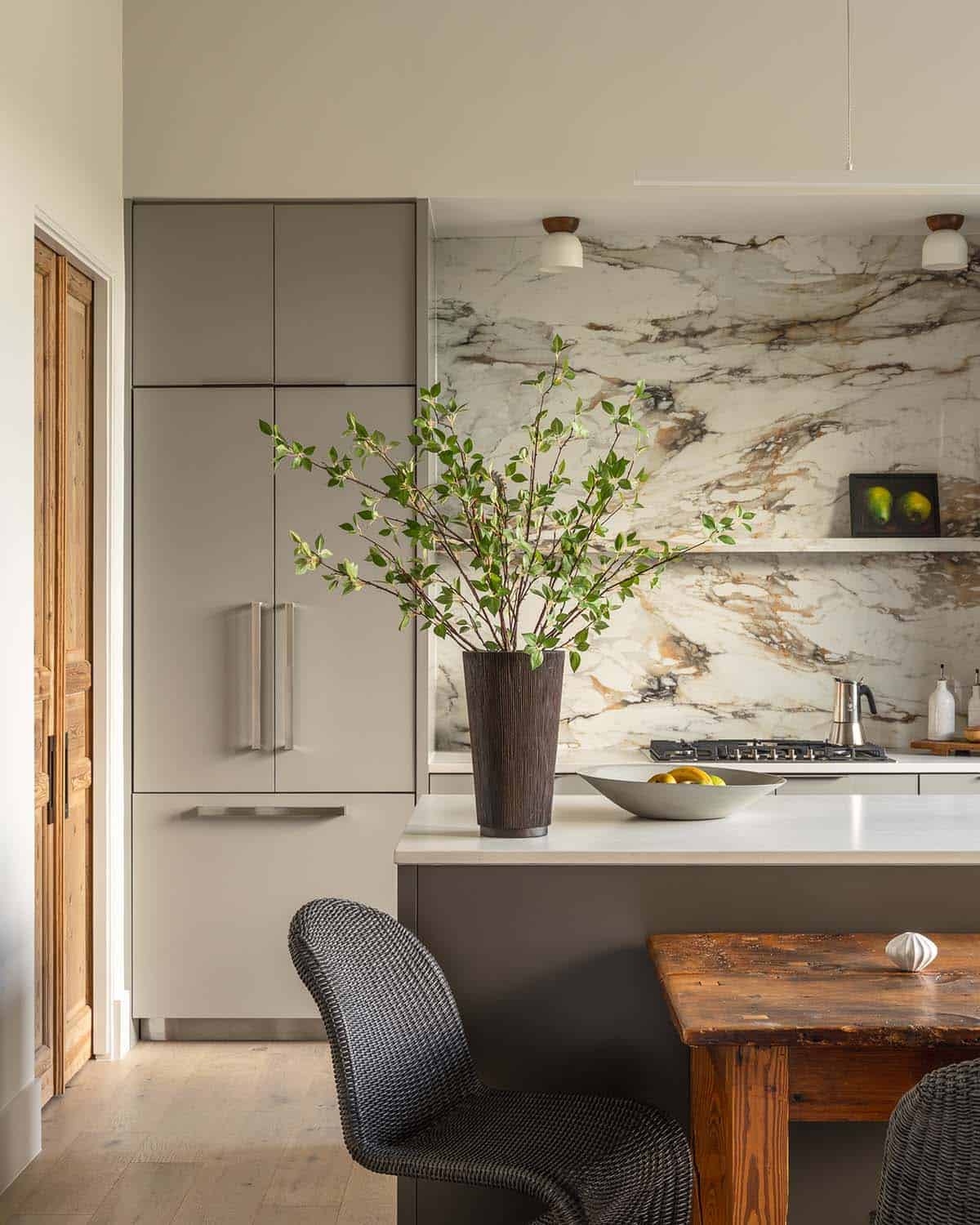 Marble slab backsplash frames a tall vase beside built-in cabinetry