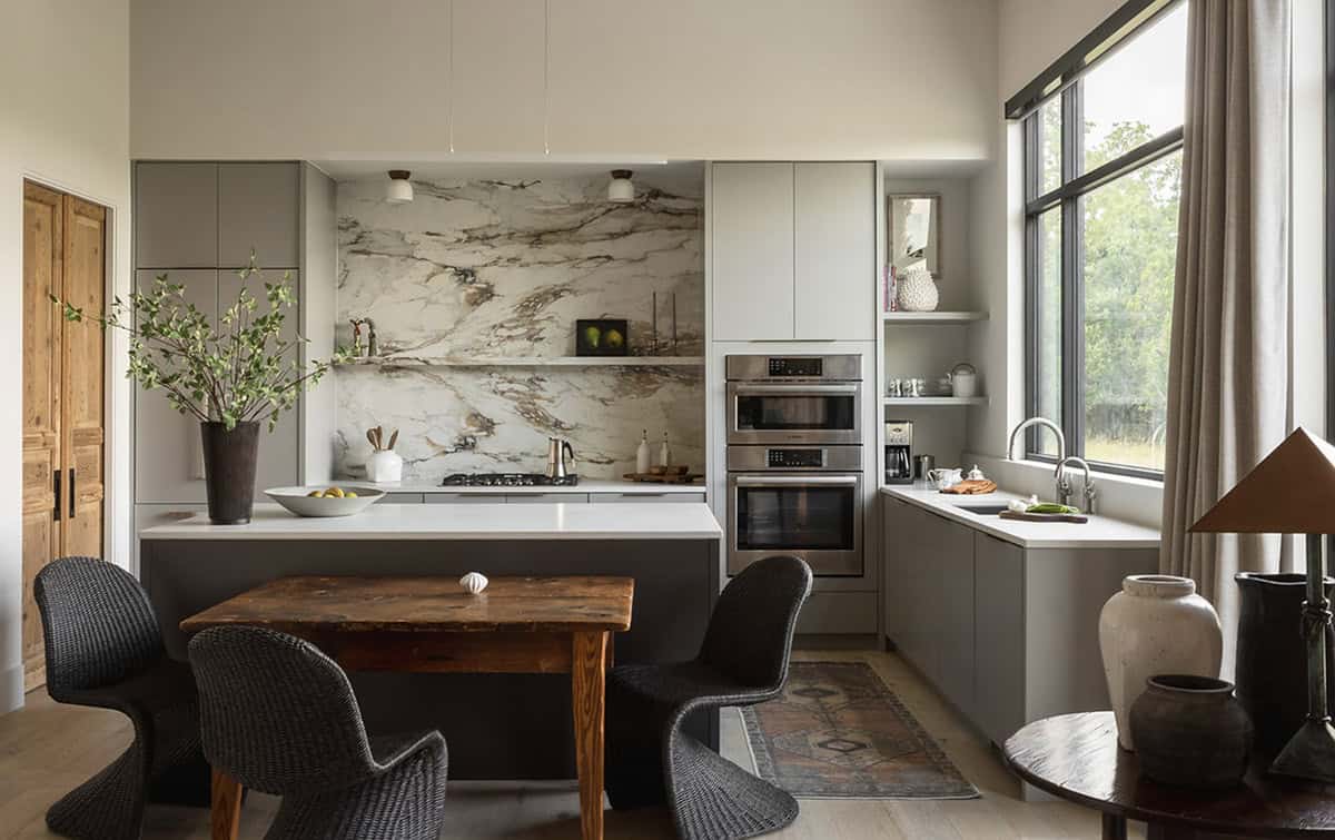 Kitchen dining nook with woven chairs beneath a dramatic marble backsplash