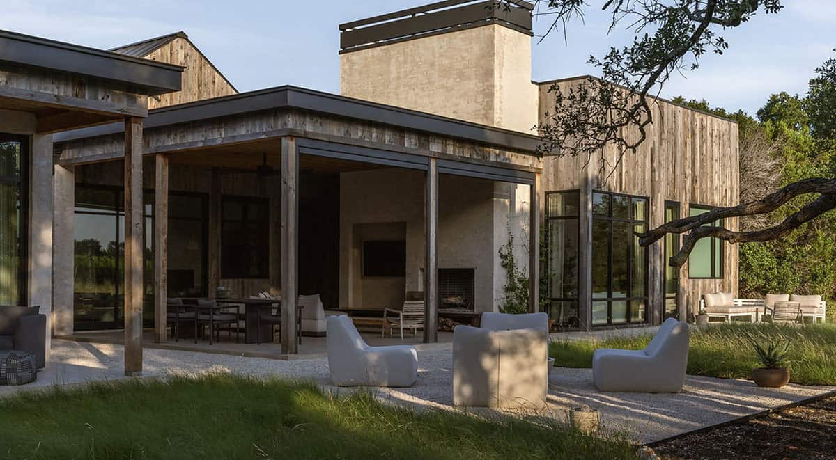 Covered patio with white lounge chairs faces the timber and stucco exterior