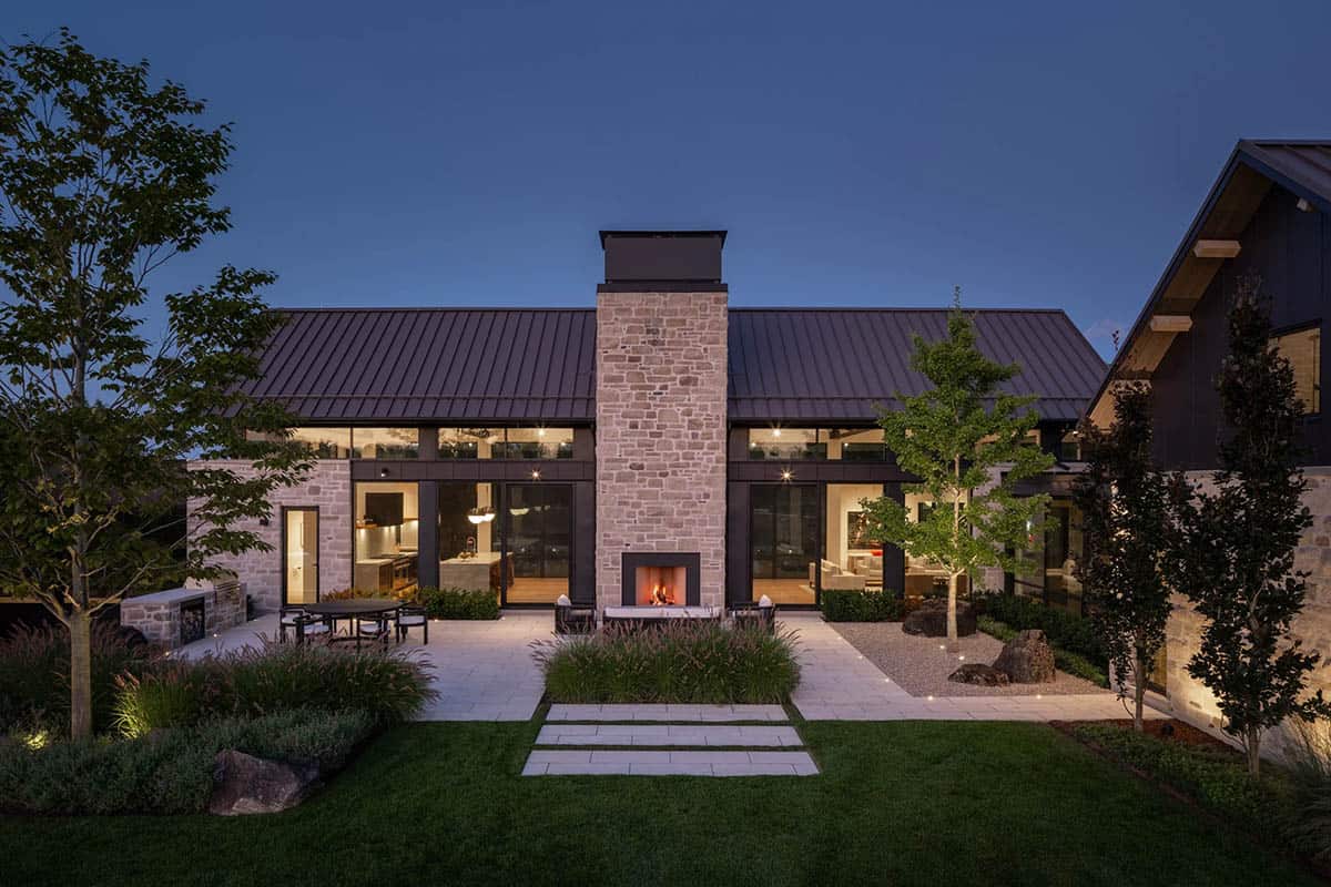 Rear courtyard with stone fireplace and glass walls opening to kitchen and living areas