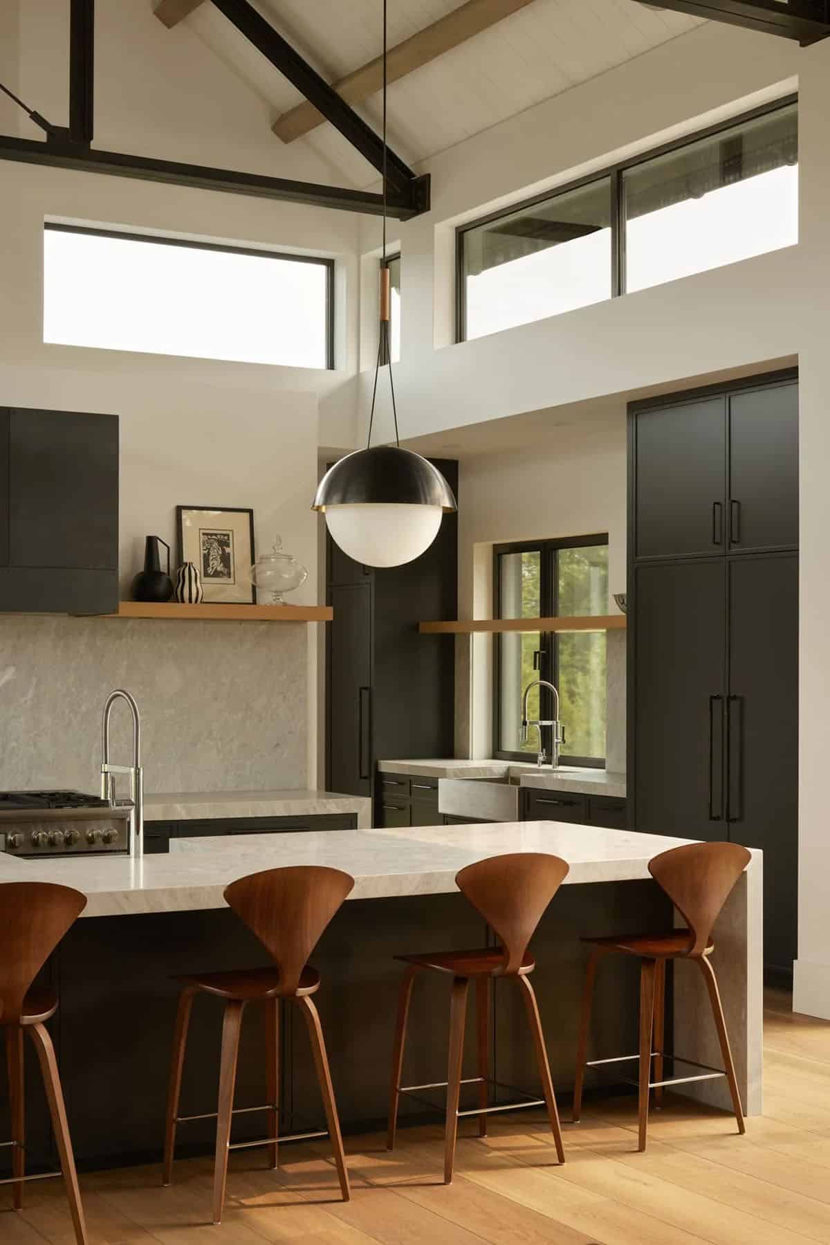 Kitchen island with dark cabinetry, marble counters, and wood bar stools