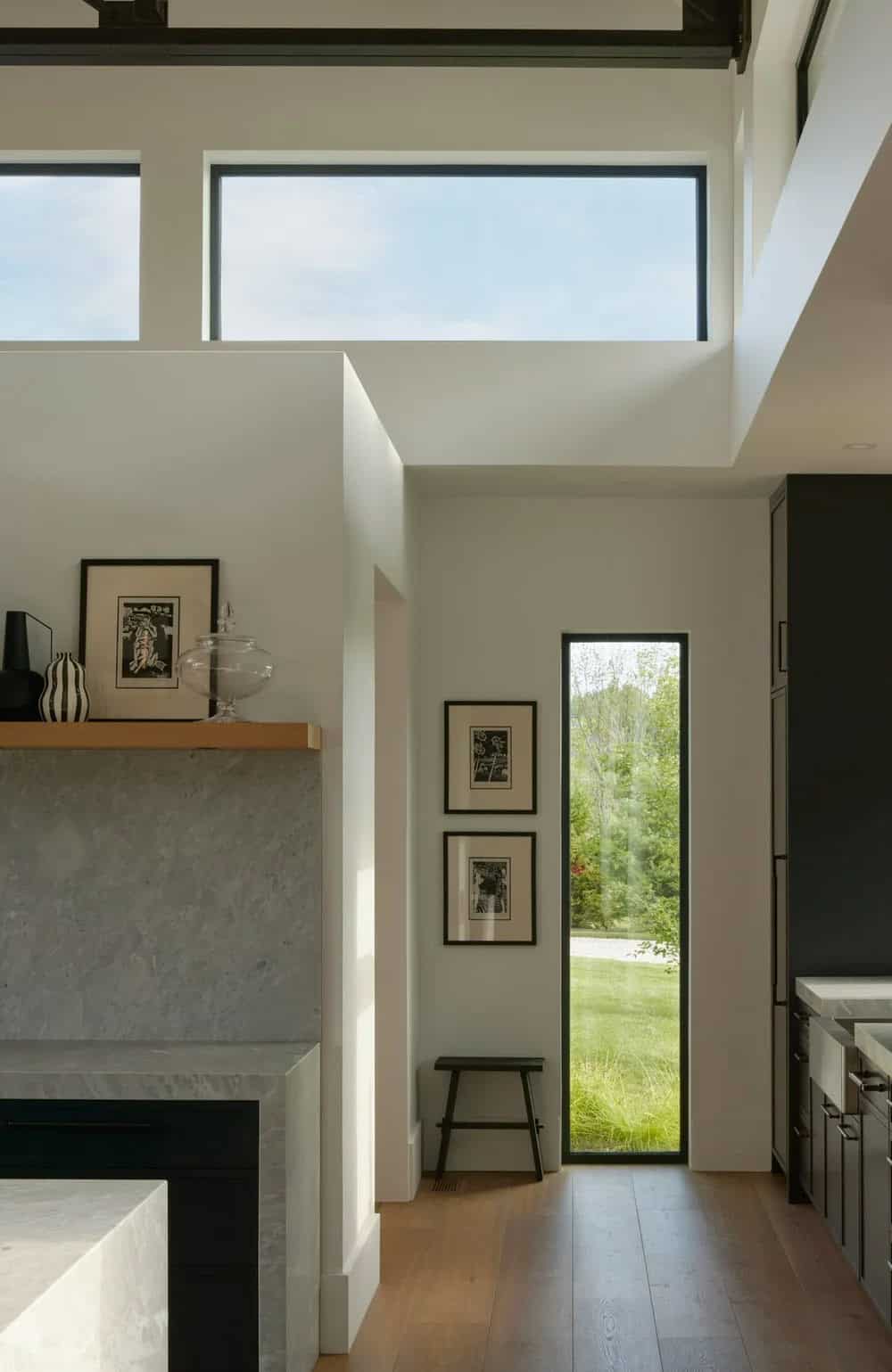 Hallway with tall narrow window, gallery wall, and stone fireplace surround