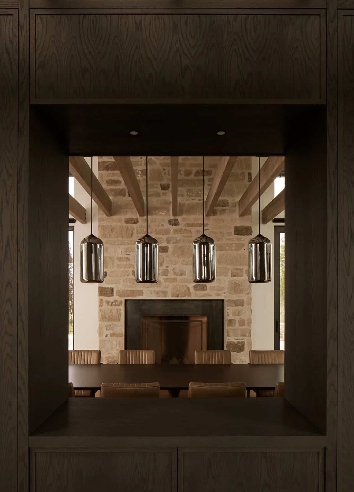 Built-in wood shelving framing view of dining table and glowing pendant lights