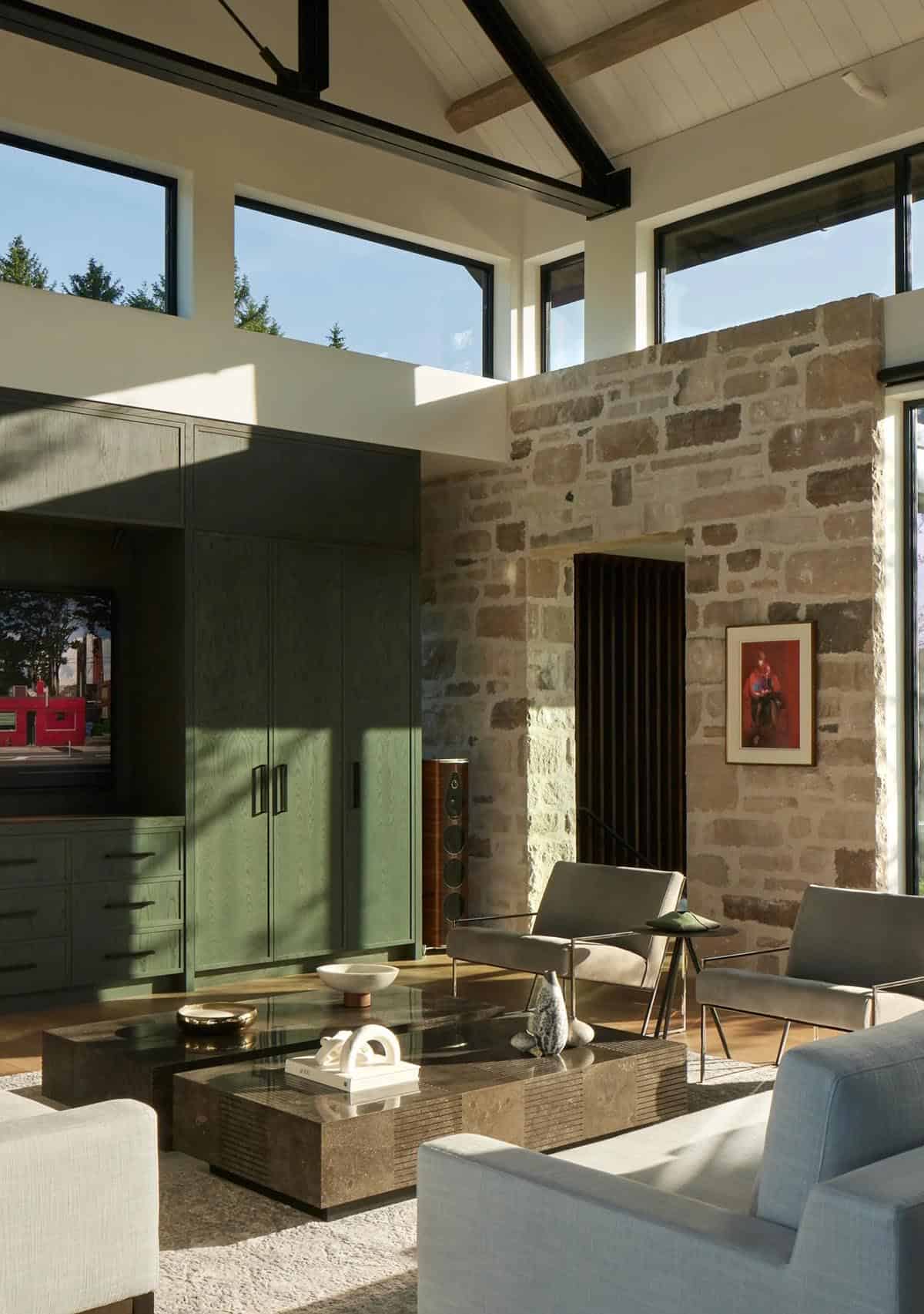 Living area with green cabinetry, stone accent wall, and layered coffee tables