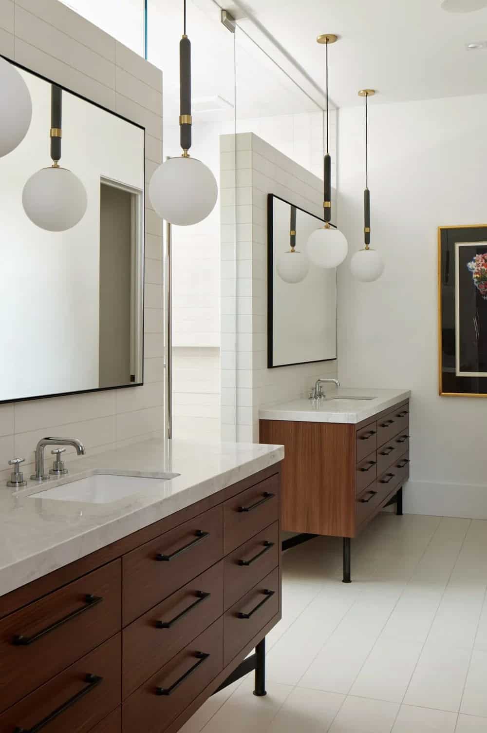 Double vanity bathroom with walnut cabinetry and hanging globe pendants