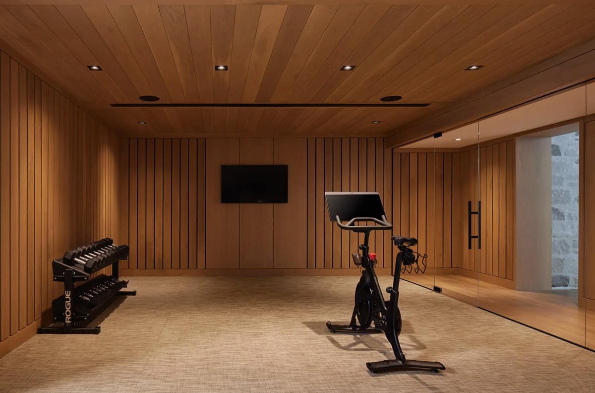 Wood-paneled home gym with exercise bike and dumbbell rack