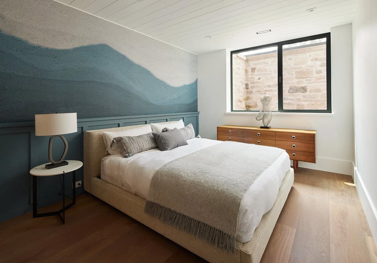 Bedroom with blue mountain-motif accent wall and walnut dresser