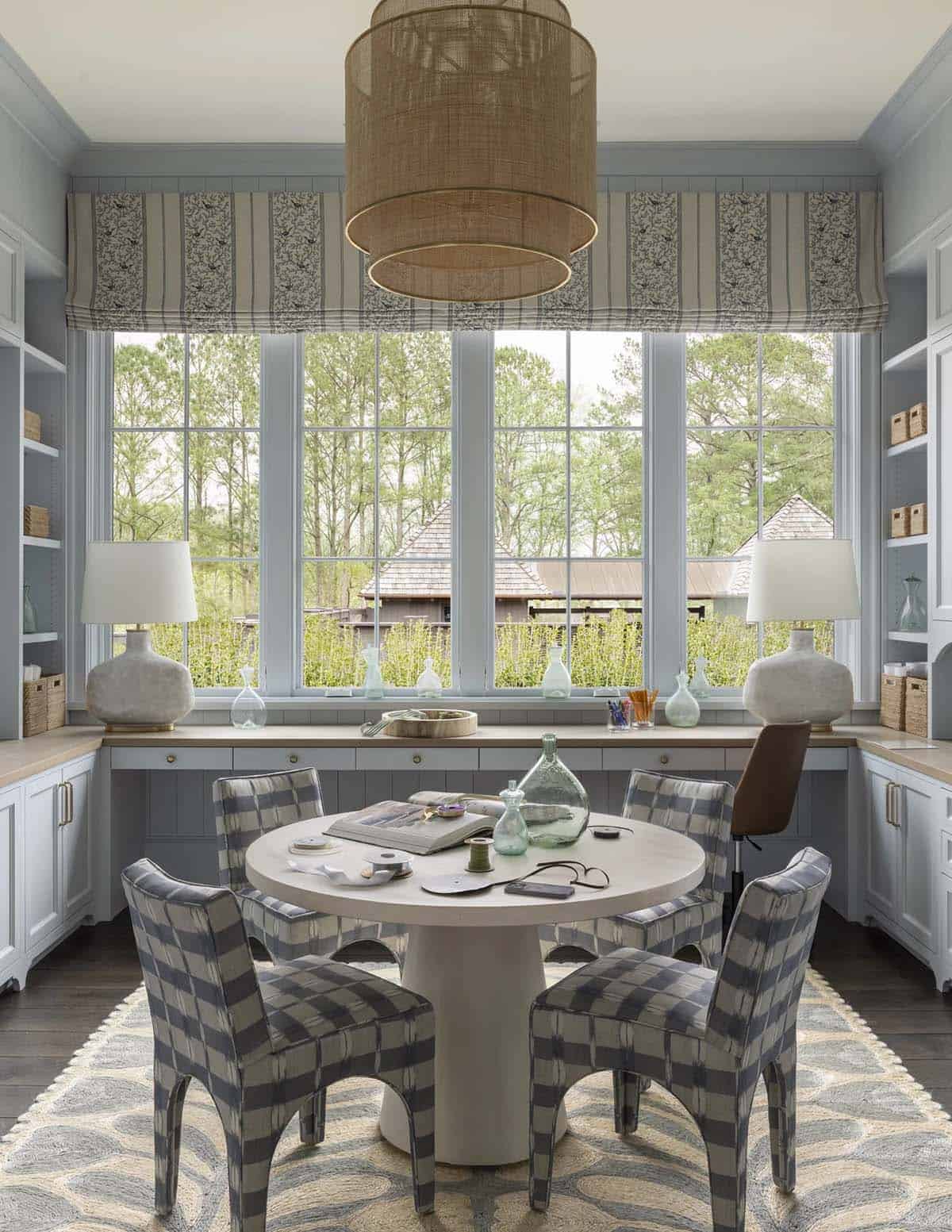 Blue built-in craft room nook with round table, plaid chairs, and woven pendant light