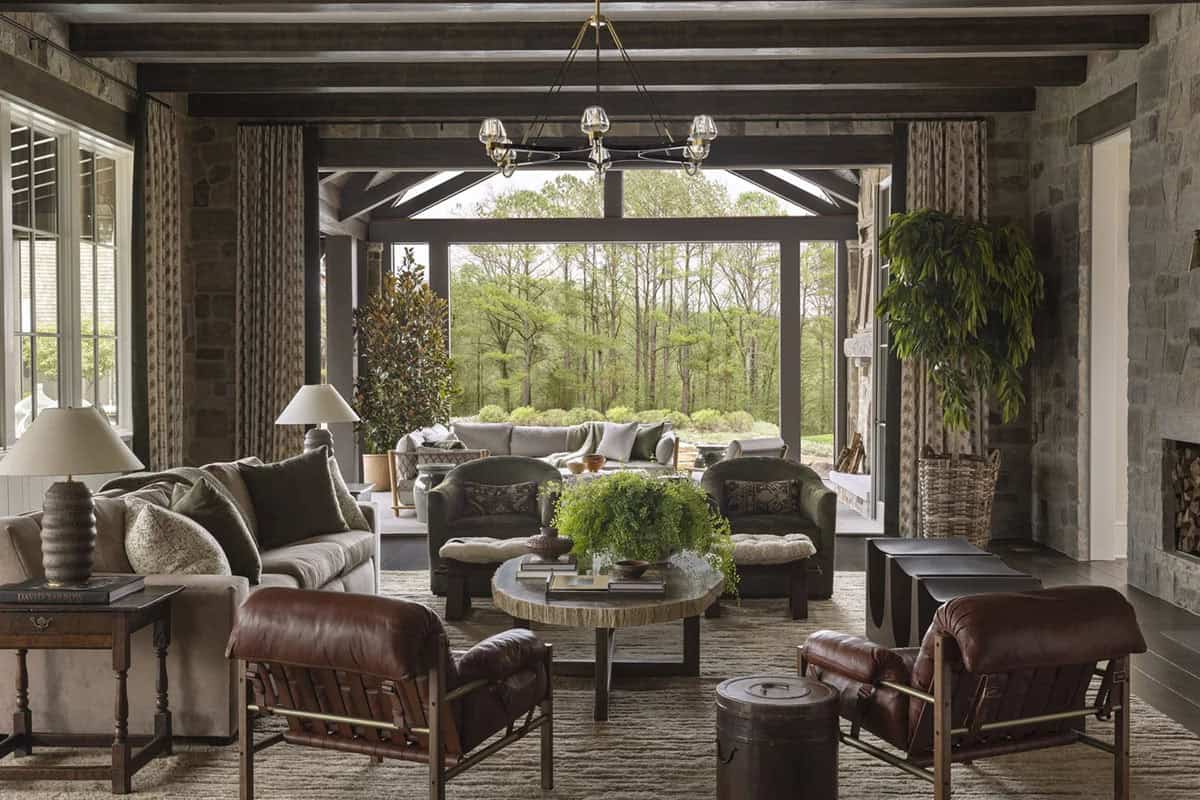 Great room with leather chairs, round coffee table, and open glass wall to a wooded yard