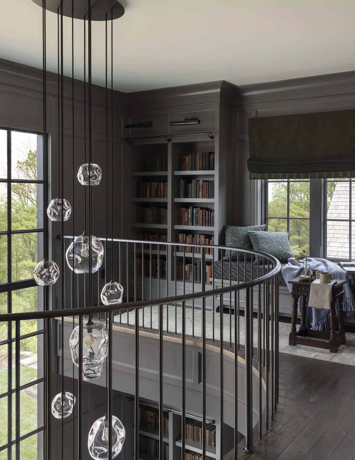 Dark library loft with spiral staircase, glass pendant lights, and window reading nook