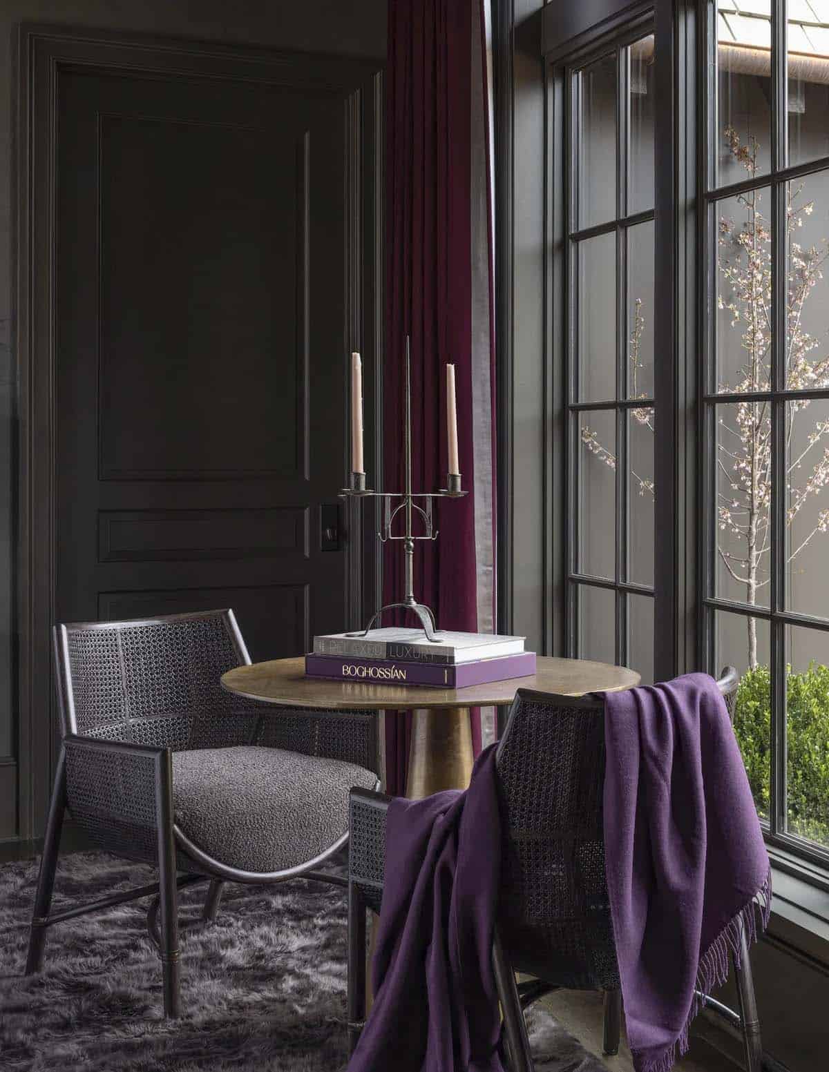 Small round table with candelabra and cane chairs draped in a purple throw