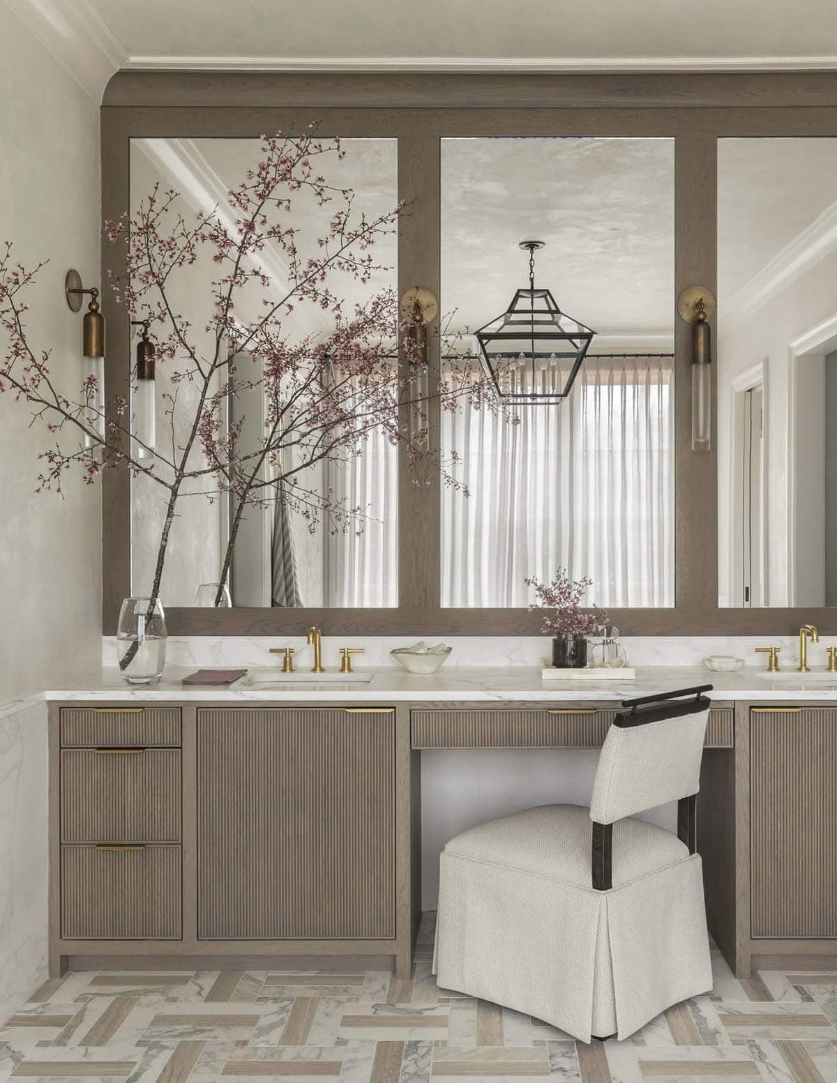 Bathroom vanity with mirrored panels, brass fixtures, and a cherry-blossom branch