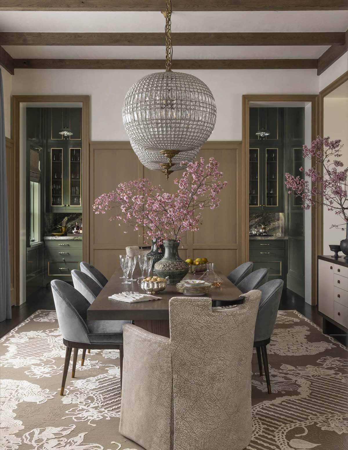 Formal dining room with a round beaded chandelier and flanking green butler's pantries