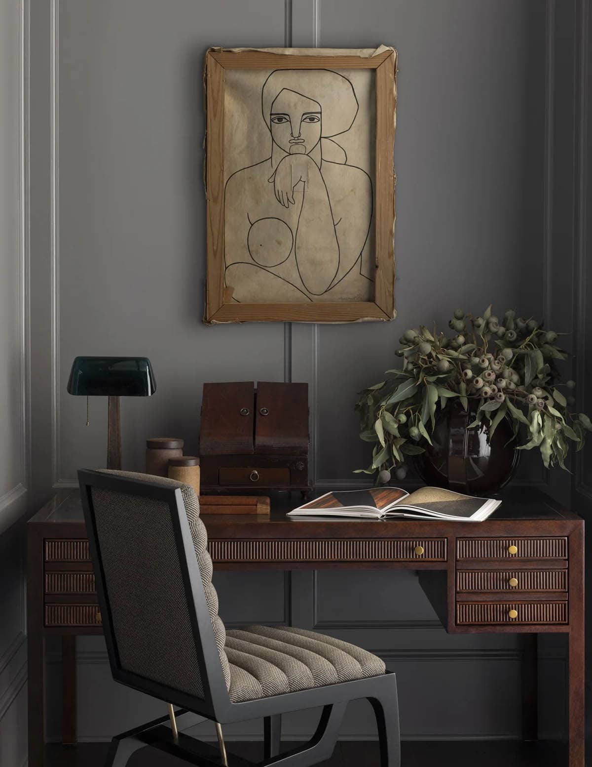 Dark study nook with a ribbed wood desk and abstract line-drawing portrait