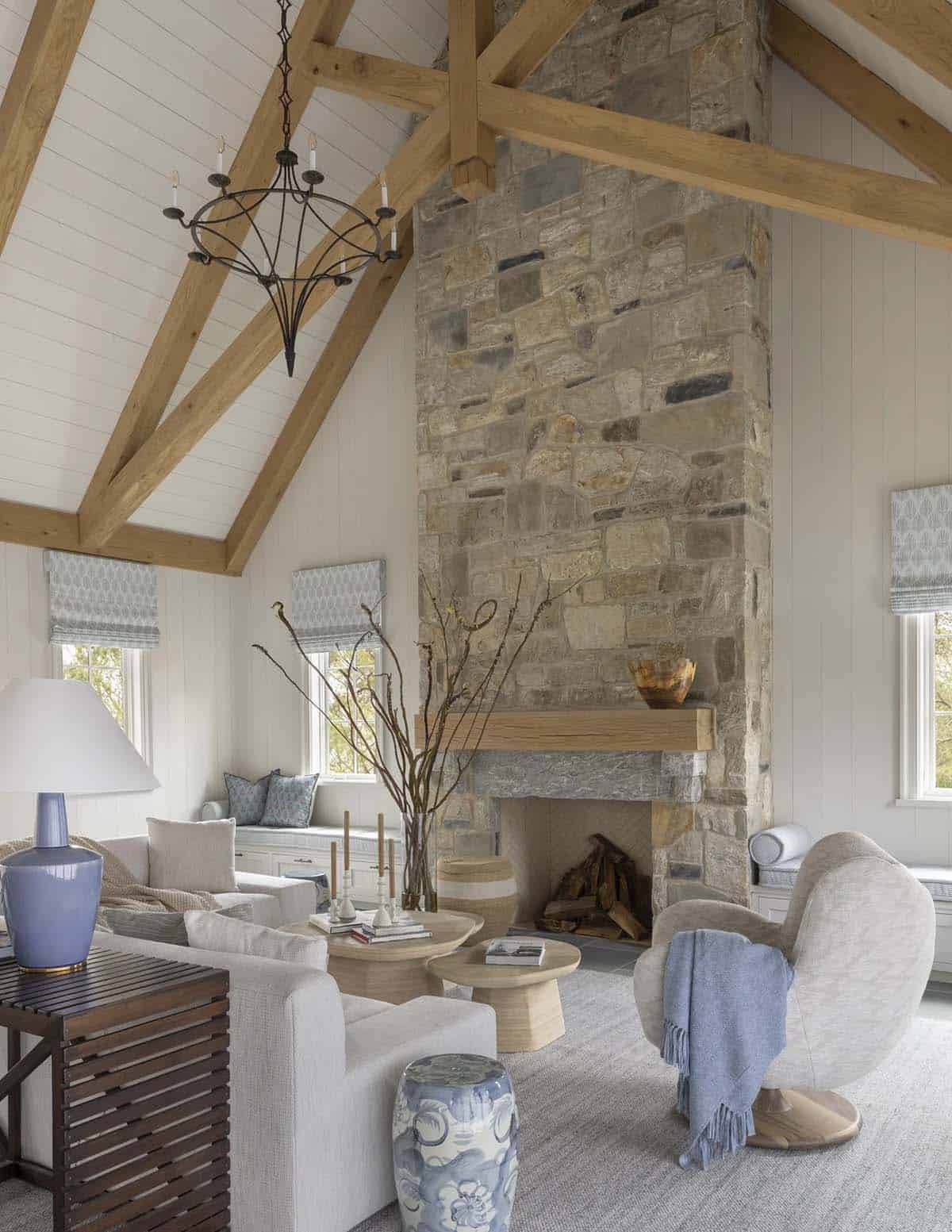 Vaulted living room with exposed wood trusses, stone fireplace, and coastal-blue accents