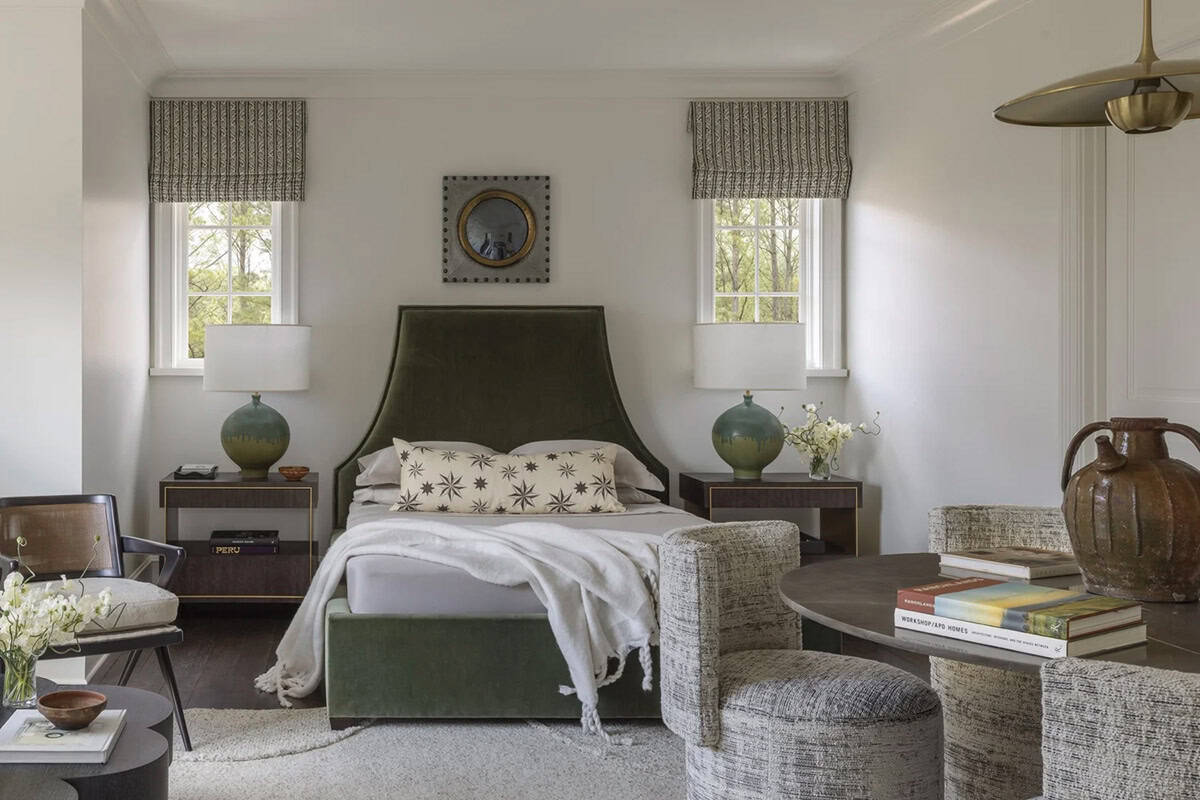 Bedroom with an olive velvet headboard, round green lamps, and a convex mirror