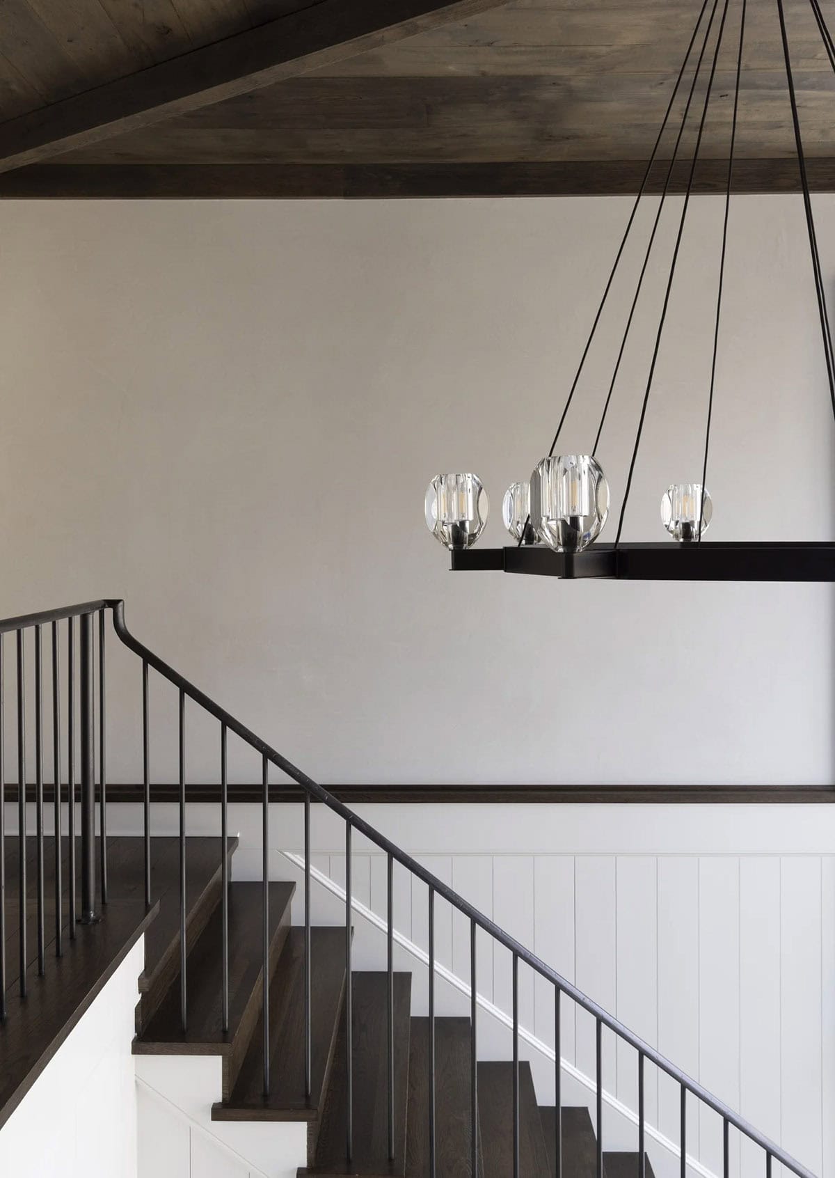 Staircase detail with iron railing and a linear crystal-orb chandelier