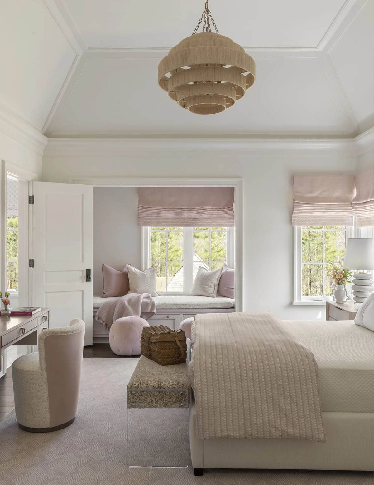 Blush-toned bedroom with a woven pendant light and a cushioned window nook