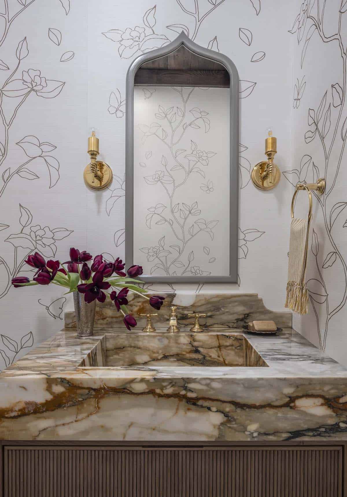 Powder room with veined marble sink, gold faucet, and floral-outline wallpaper