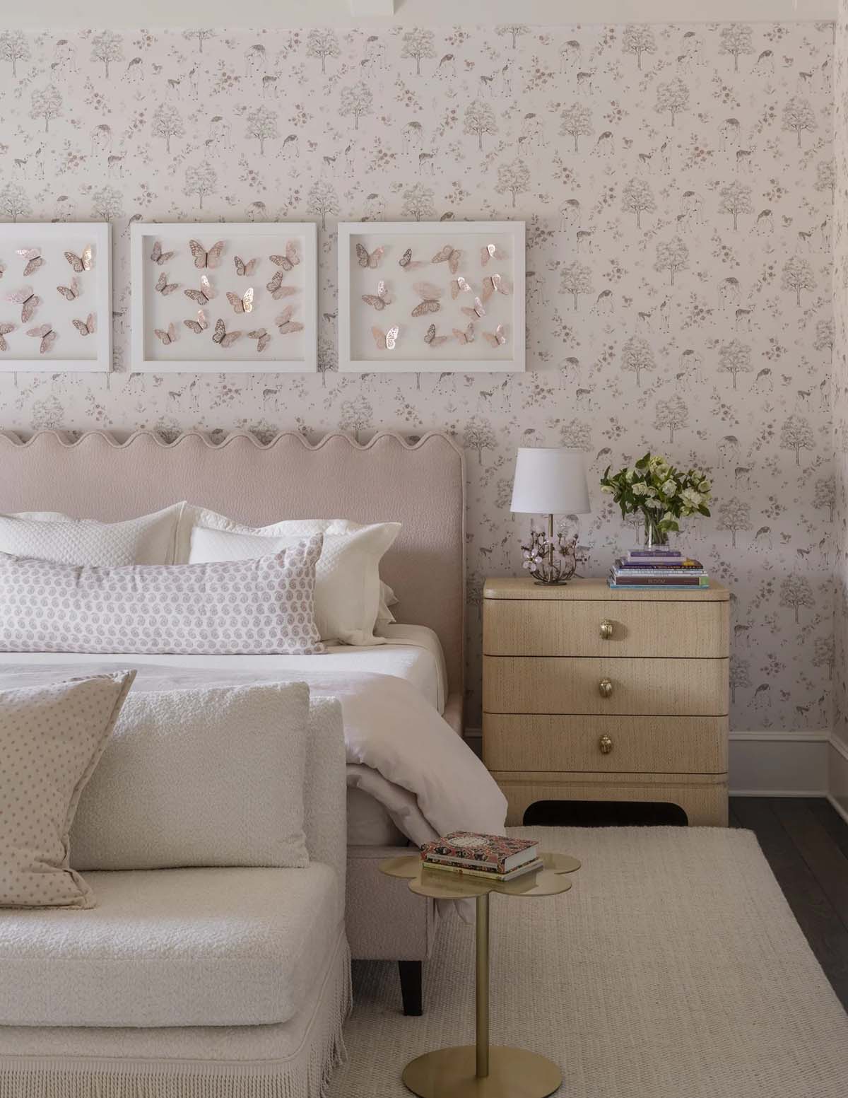 Girl's bedroom with scalloped headboard, animal-print wallpaper, and framed butterflies