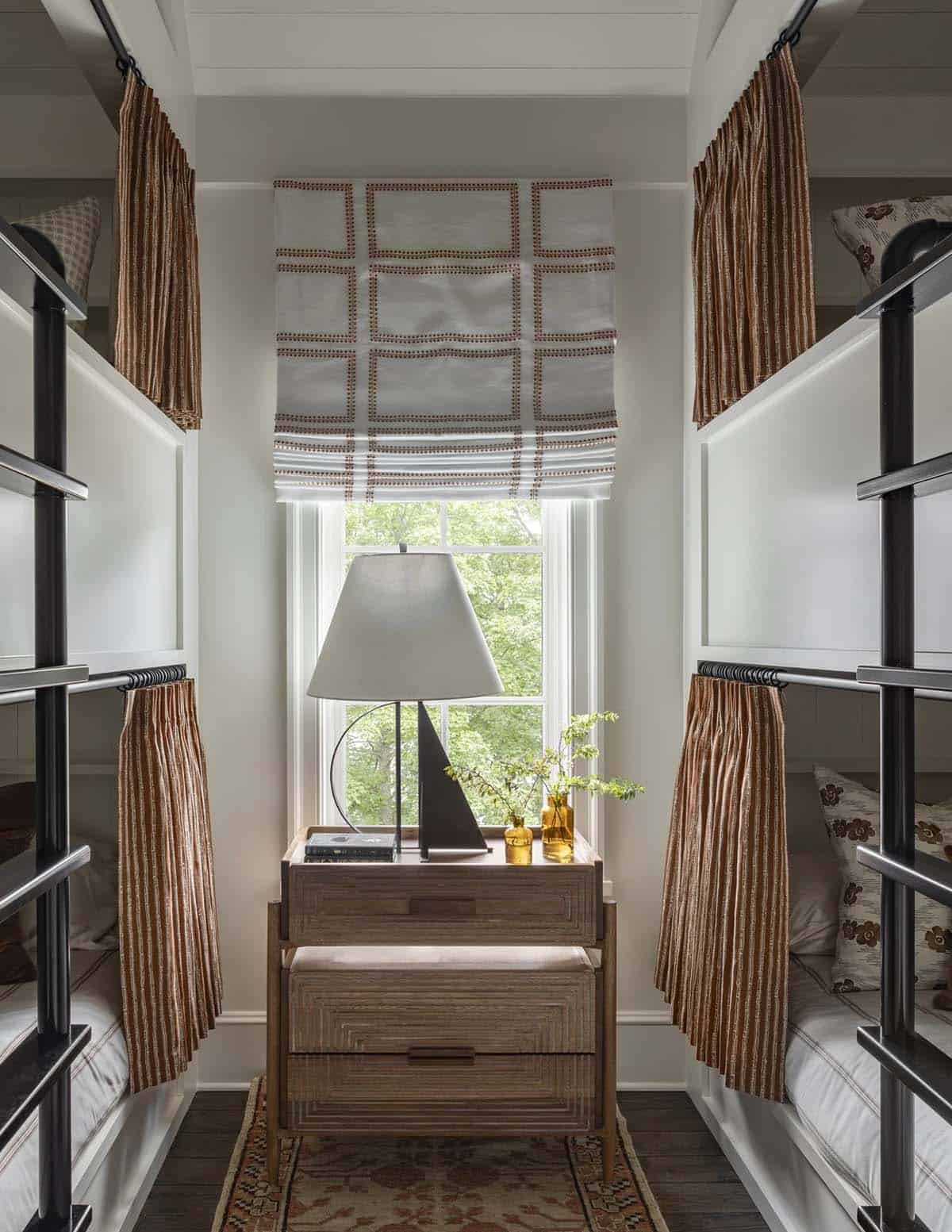 Built-in bunk room nook with striped curtains, wood nightstand, and window view