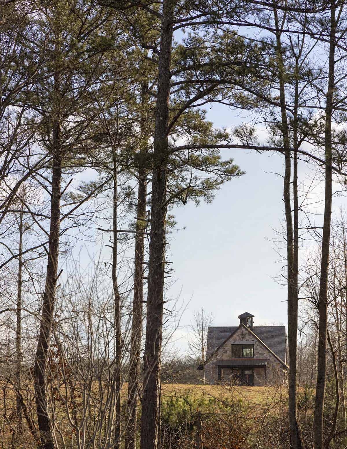 Distant view of the stone guest house framed by tall pine trees