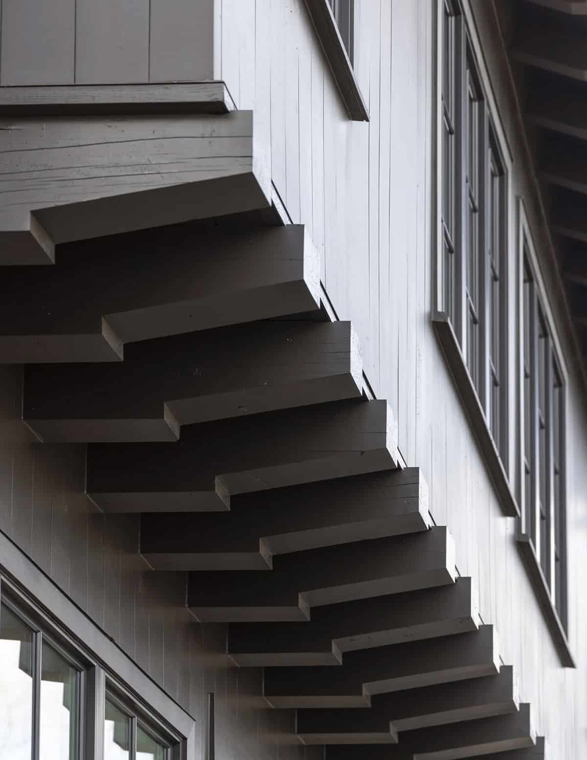 Close-up of a dark exterior staircase against white board-and-batten siding
