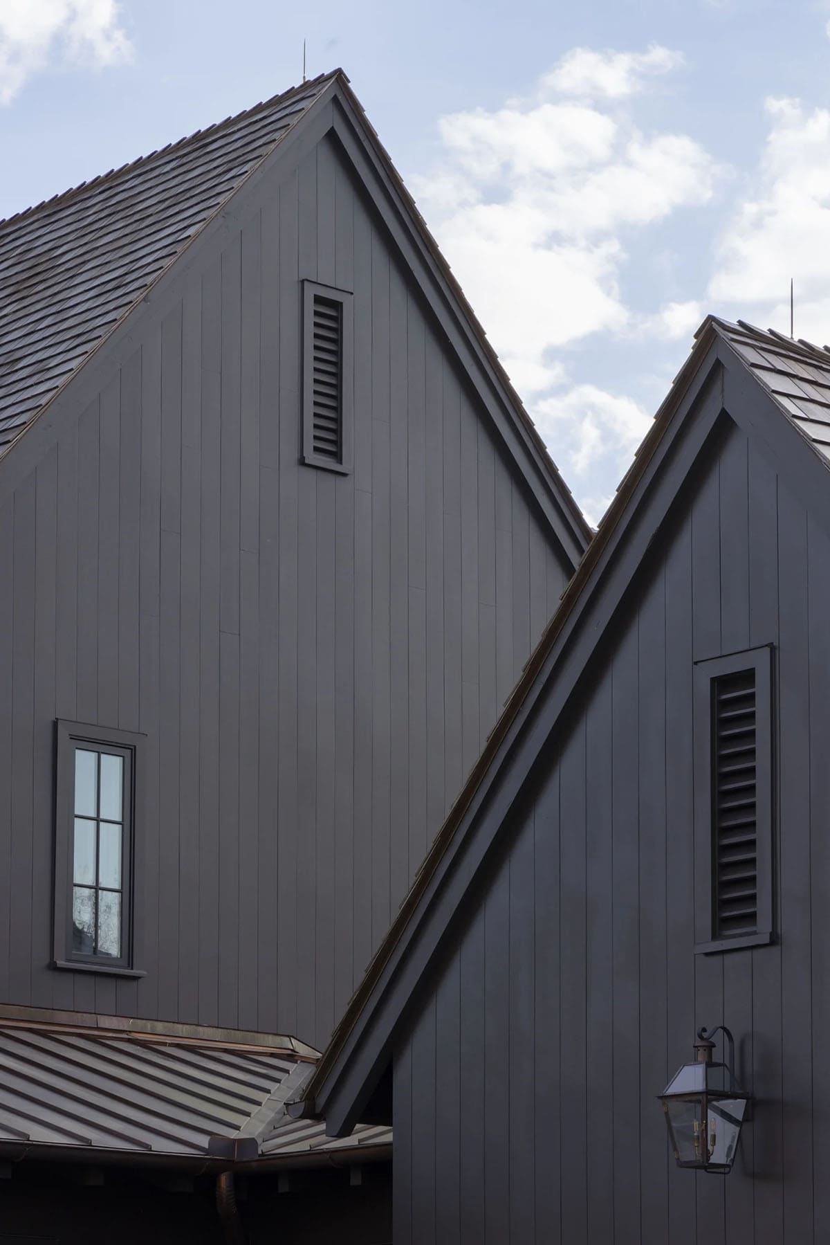 Exterior detail of crossing dark gable roofs with louvered vents