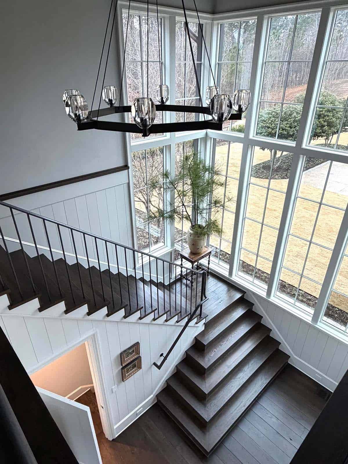Overhead view of a wood staircase landing beneath a crystal wagon-wheel chandelier