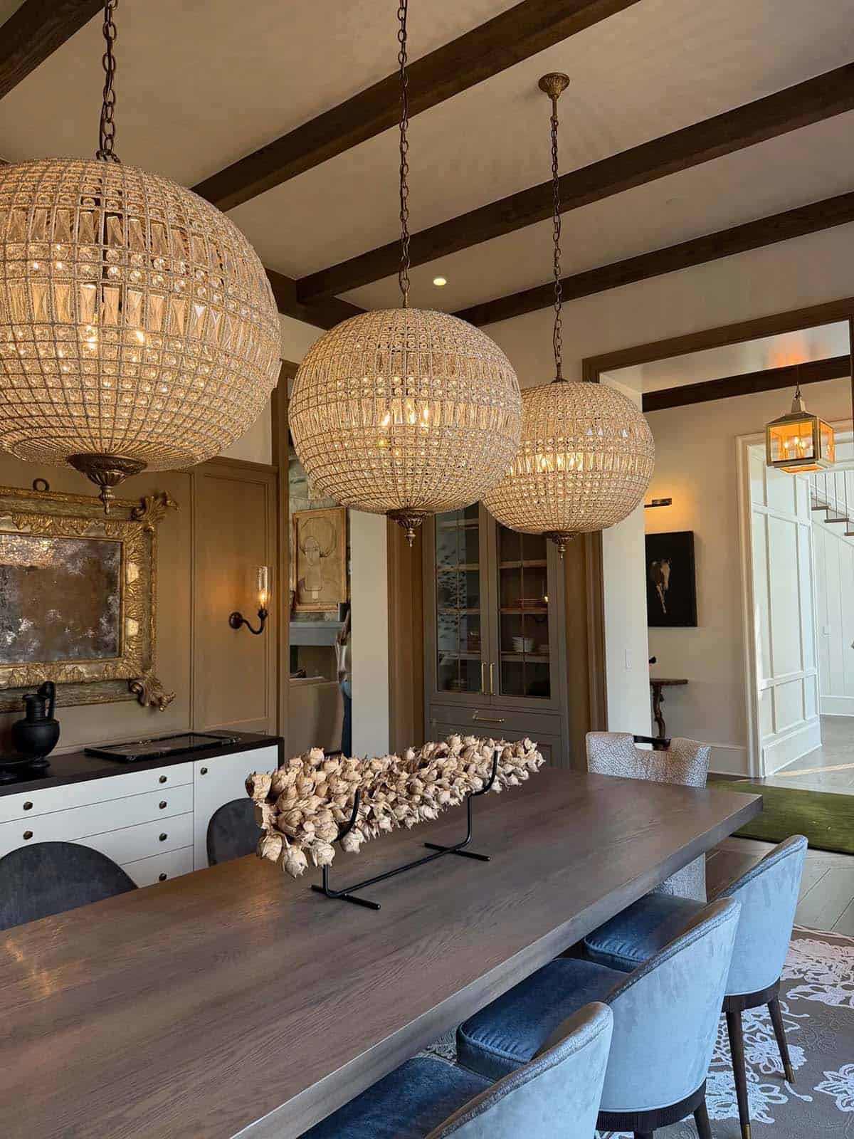 Dining room with three large beaded-glass globe chandeliers over a wood table