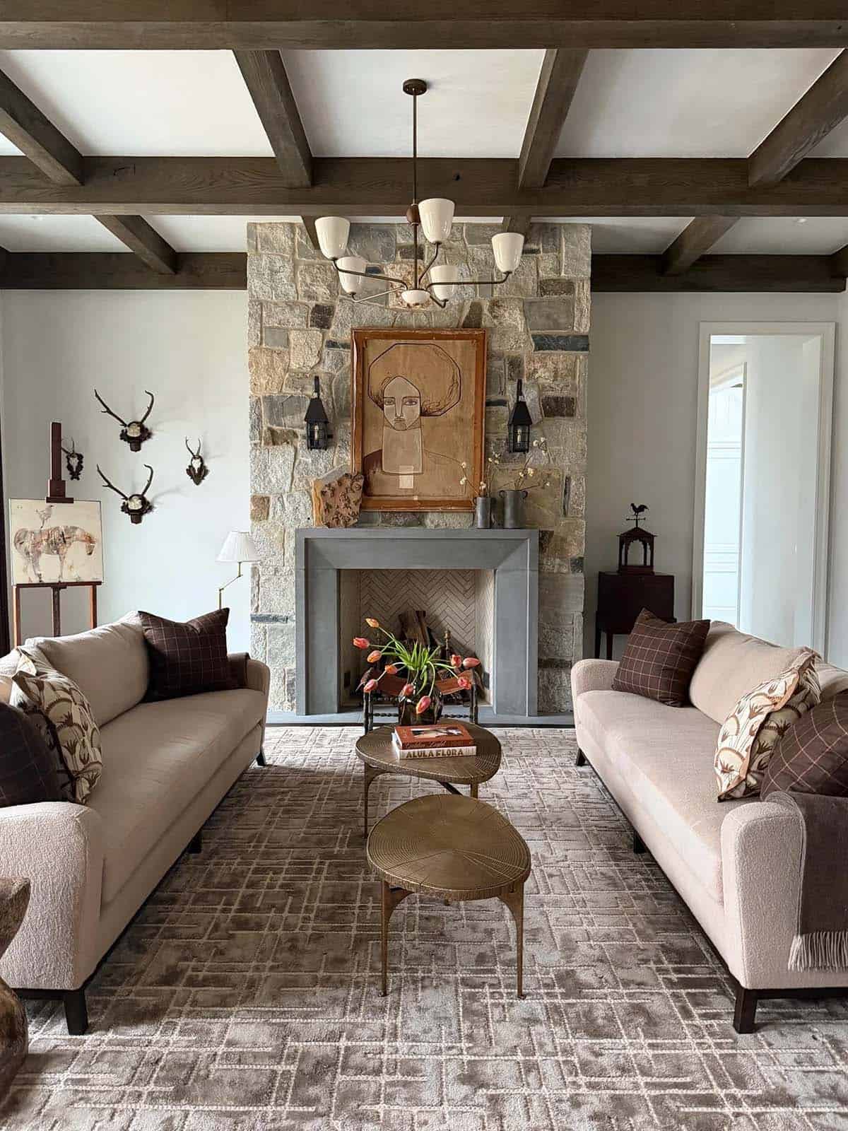 Living room with twin beige sofas facing a stone fireplace and antler-mounted wall
