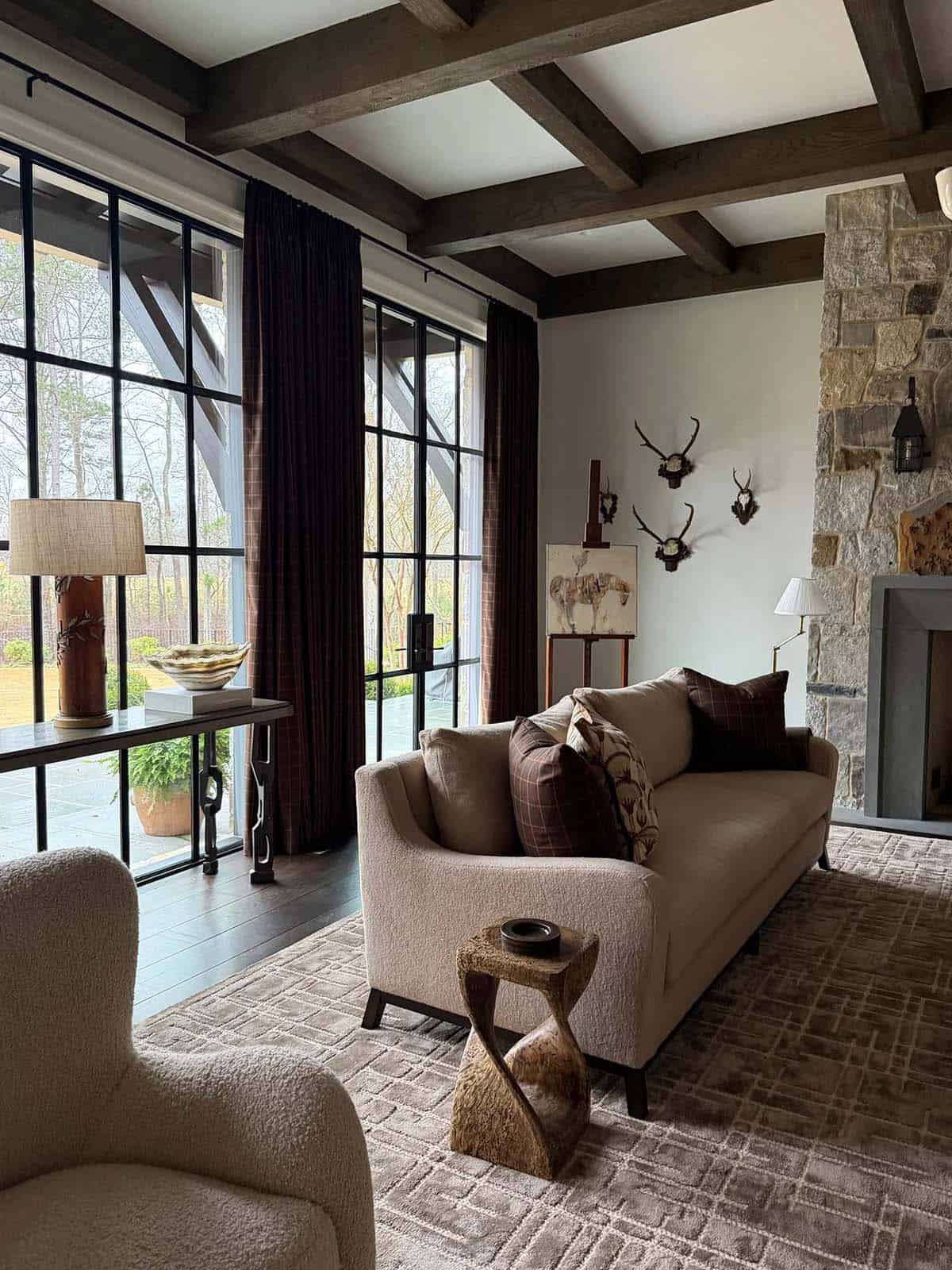 Living room corner with boucle sofa, sculptural side table, and mounted antlers