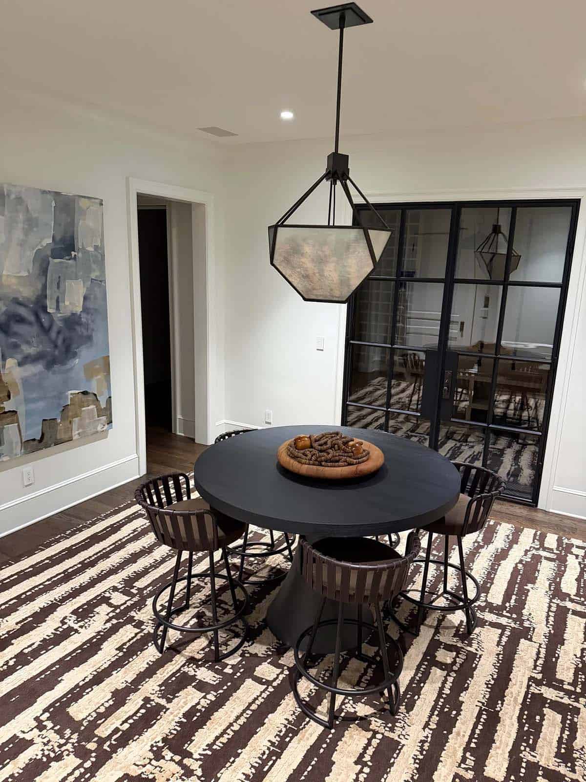 Round black breakfast table with woven counter stools and abstract art