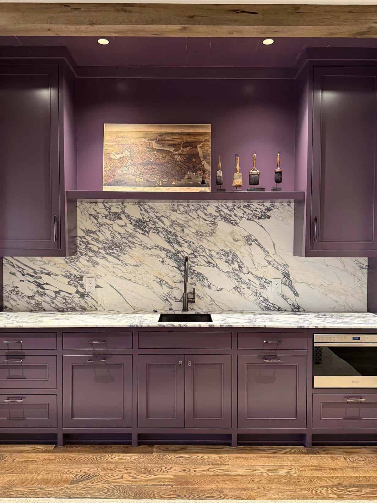 Purple butler's pantry with marble backsplash and antique paintbrush display