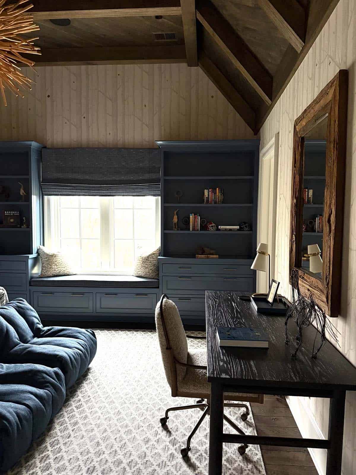 Kid's study nook with blue window seat, dark desk, and rustic wood mirror