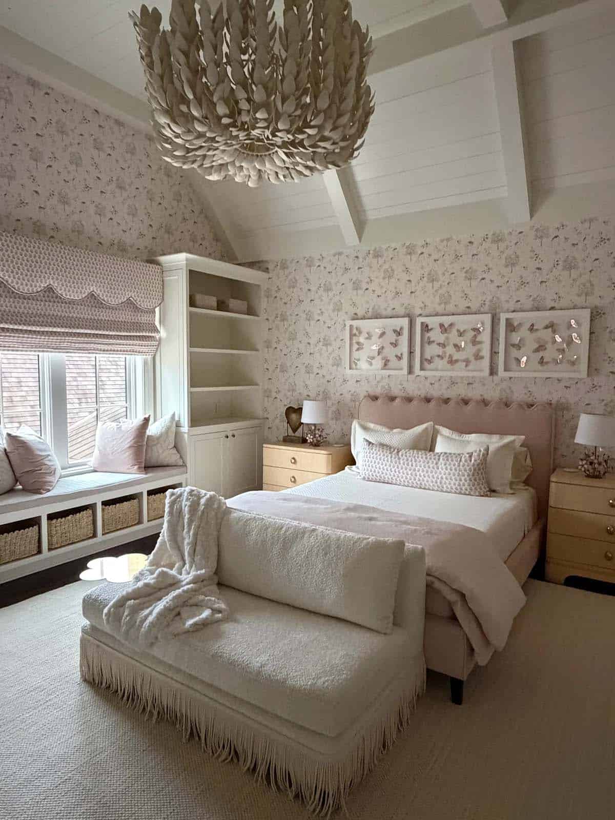 Girl's bedroom with feathered chandelier, window seat, and floral wallpaper