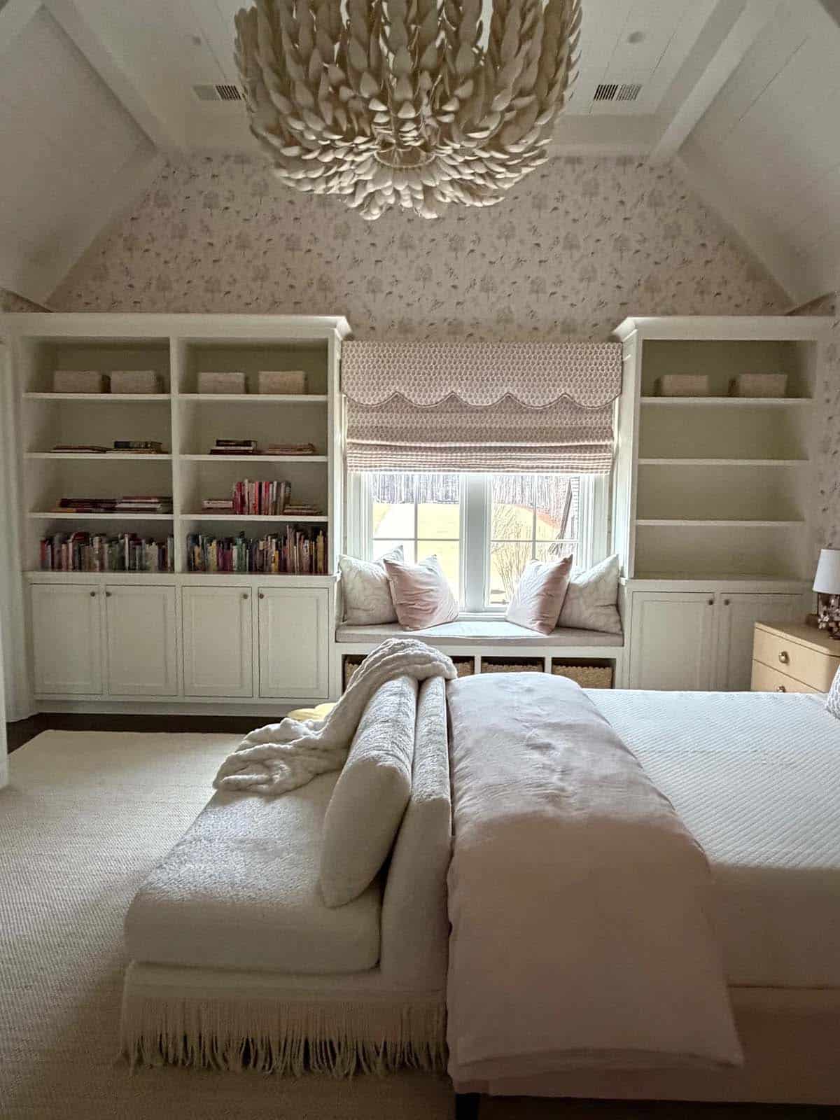 Girl's bedroom with white built-in bookshelves and a pink-cushioned window nook