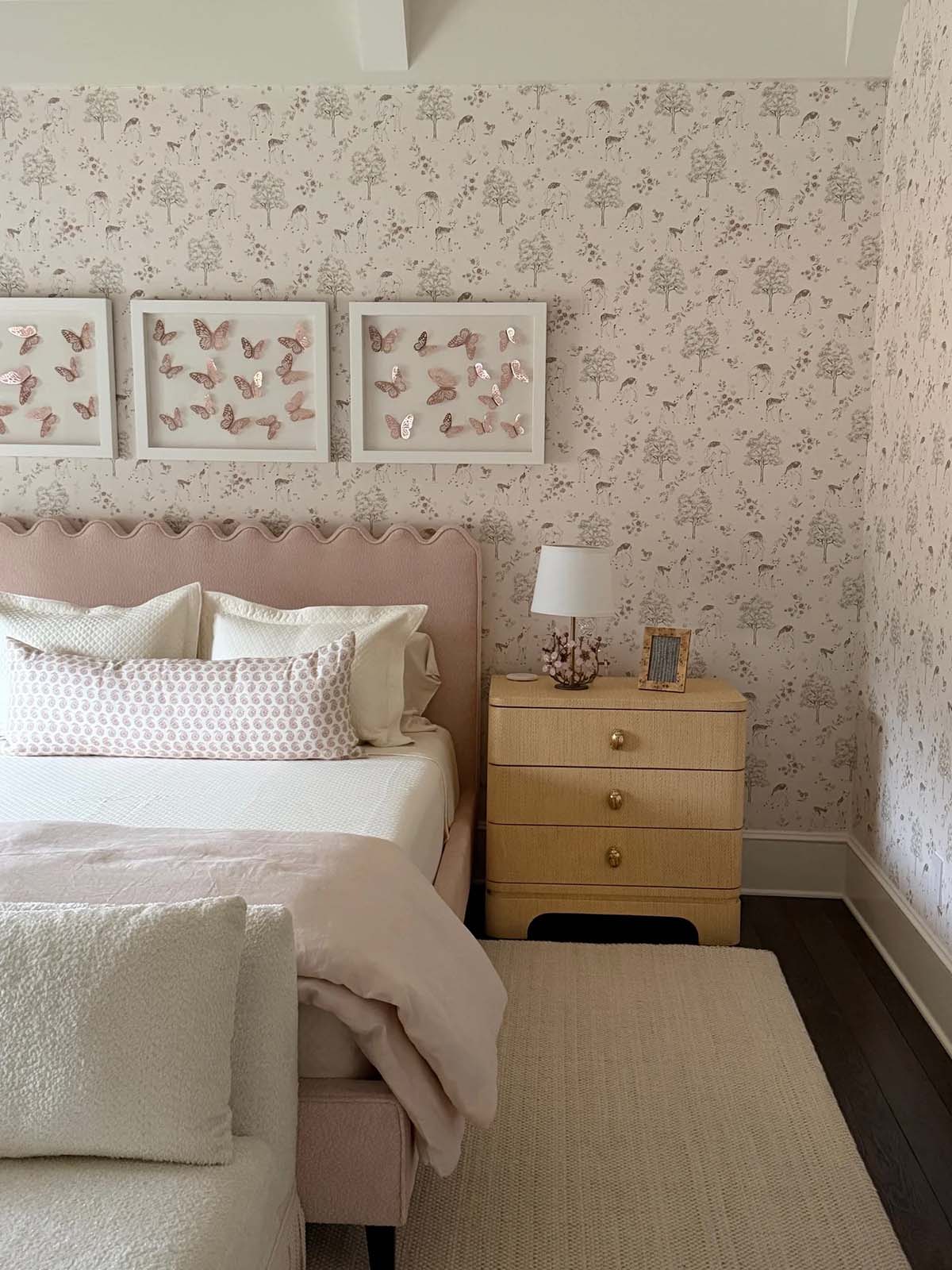 Bedroom nightstand vignette with woven dresser and framed butterfly art