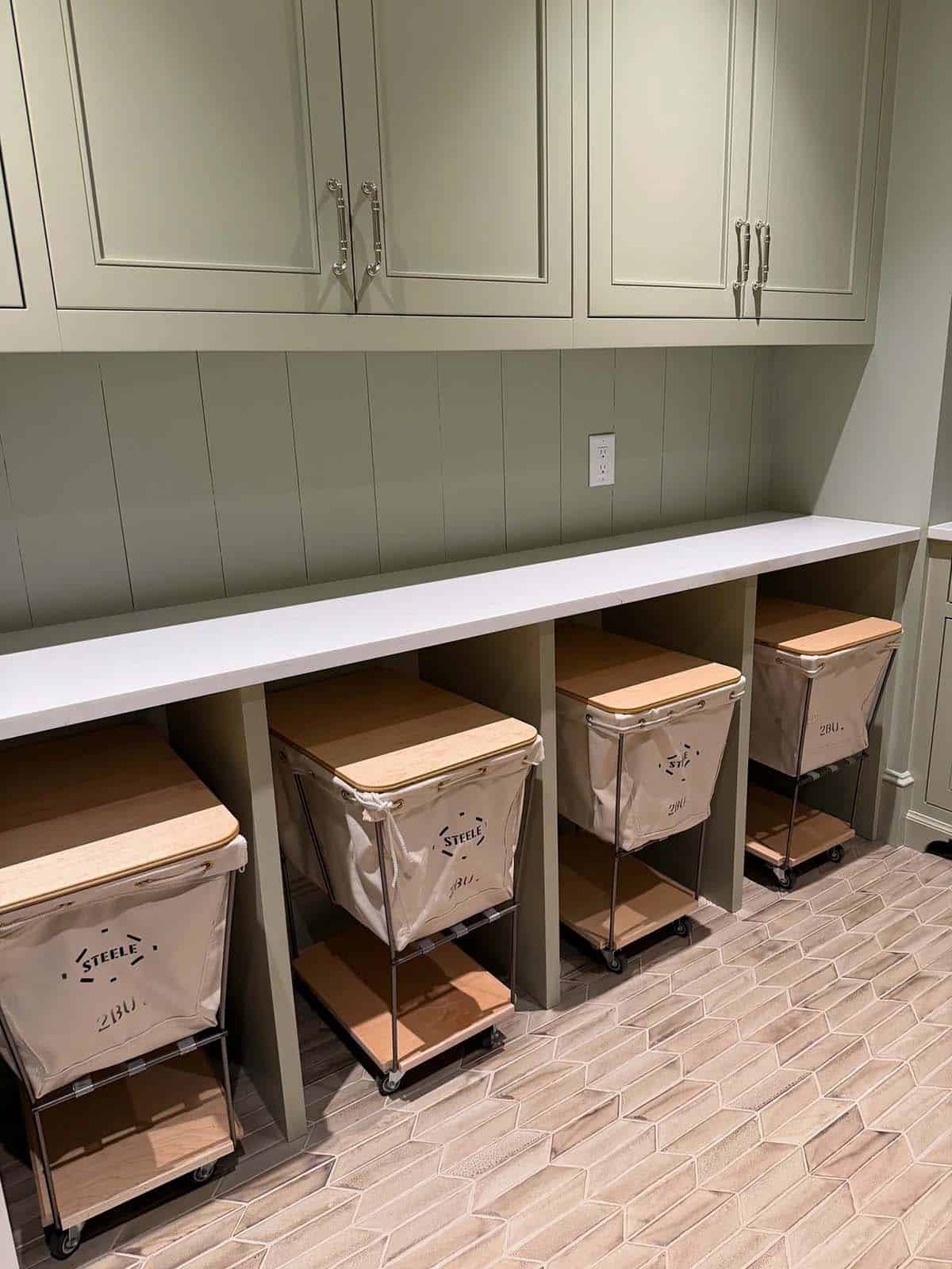 Sage green mudroom cubbies with rolling canvas laundry hampers