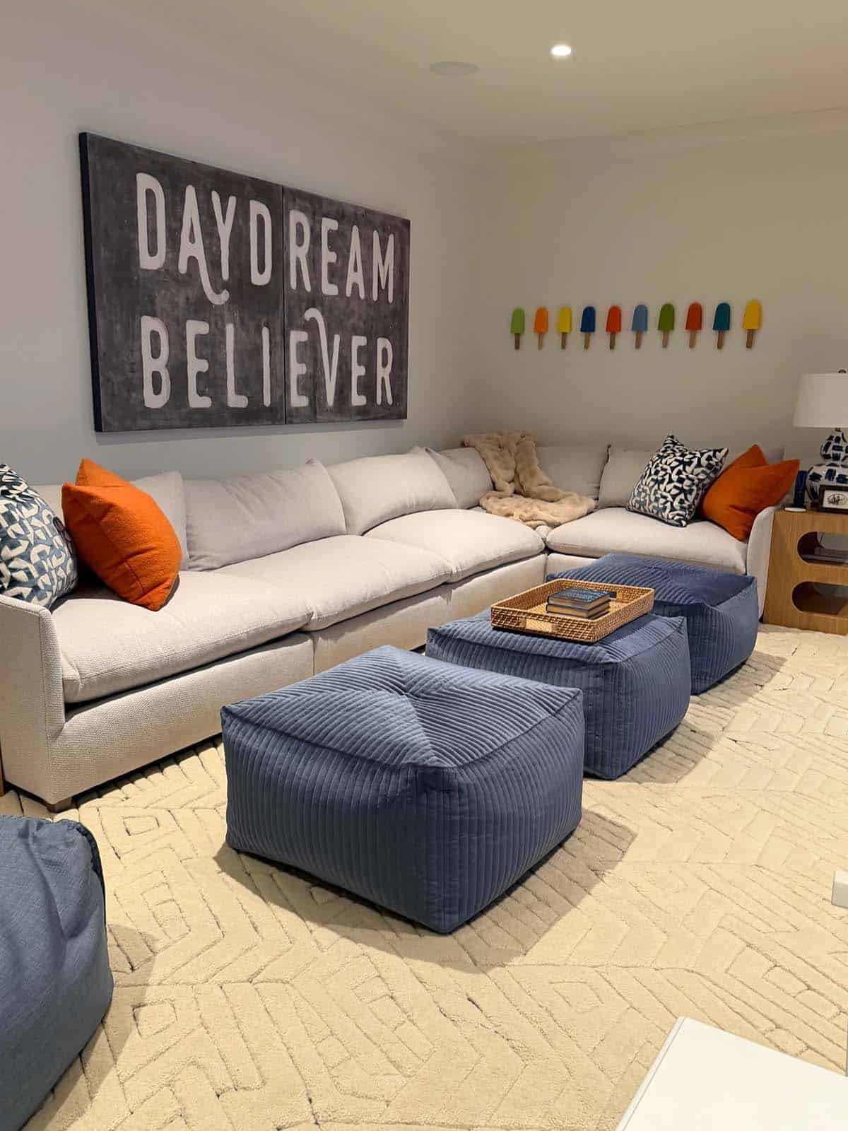 Playroom with "Daydream Believer" wall art, popsicle decor, and blue corduroy poufs