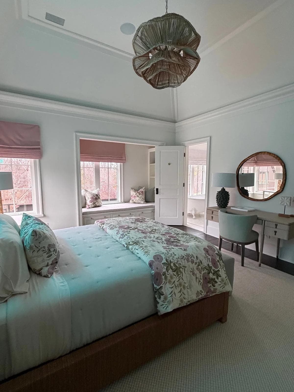 Bedroom with a woven shell pendant, tufted teal bed, and floral-print bedding