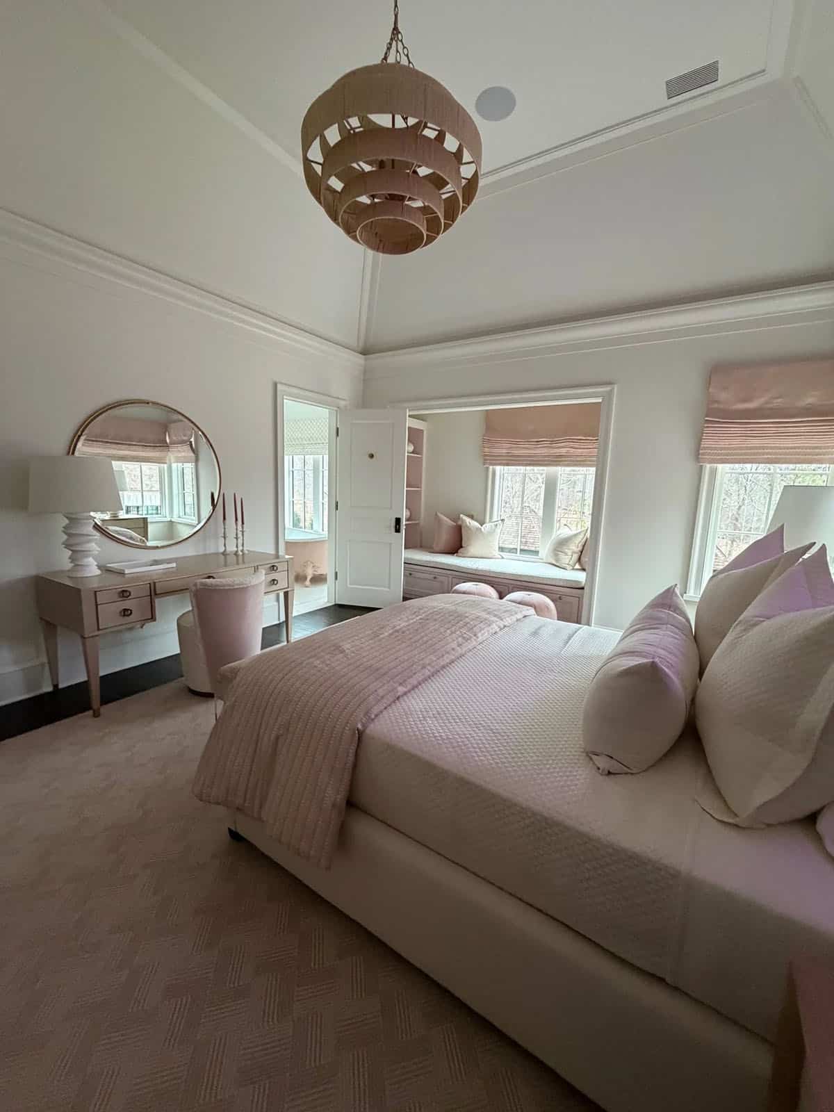 Blush bedroom with a tiered pink pendant light and a window seat alcove