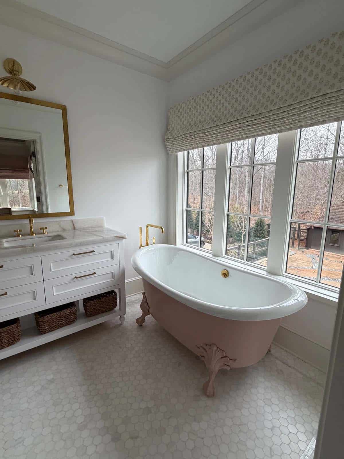 Bathroom with blush clawfoot tub, brass fixtures, and hexagon tile flooring
