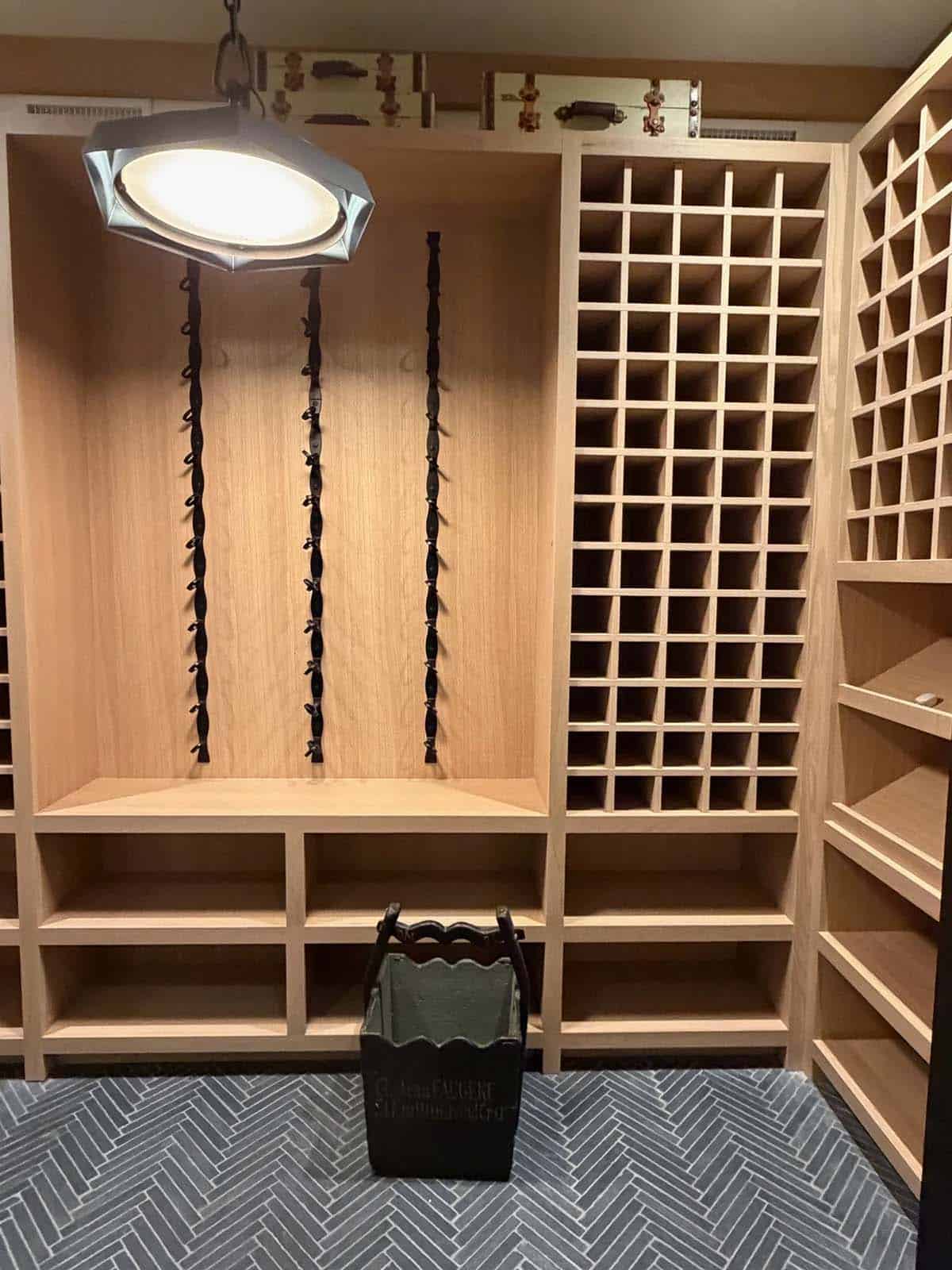 Wine cellar with light-oak diamond bottle racks and herringbone tile flooring