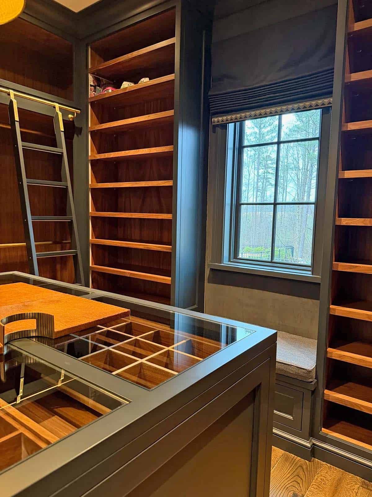 Cedar-lined closet with glass-top island storage, ladder, and window seat nook