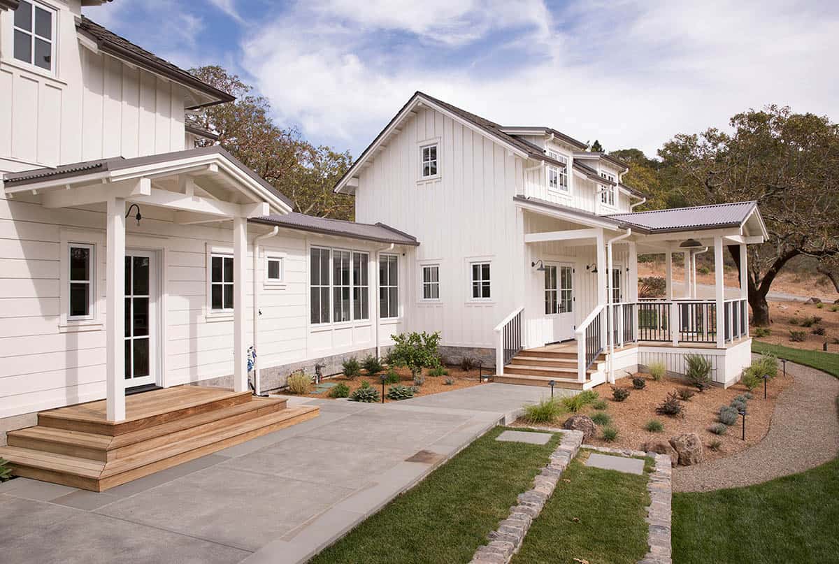 Side exterior showing covered porches, wood steps, and landscaped pathway