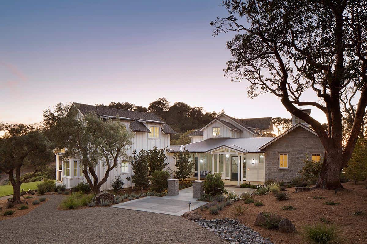 Farmhouse entrance at dusk with stone facade and warmly lit windows