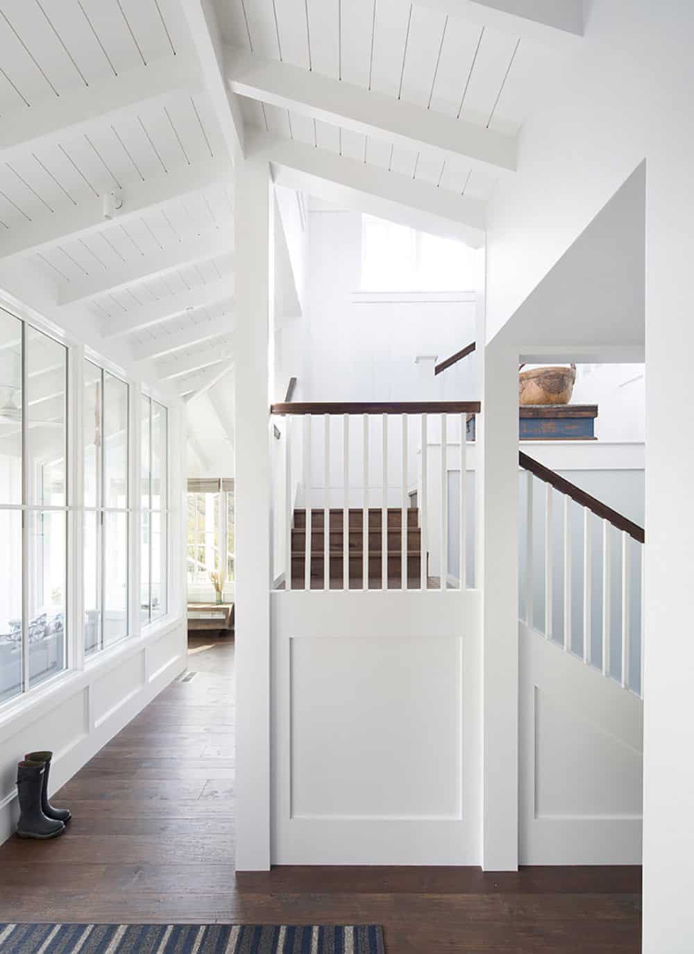 Interior stairwell with white paneling, dark wood treads, and vaulted beam ceiling